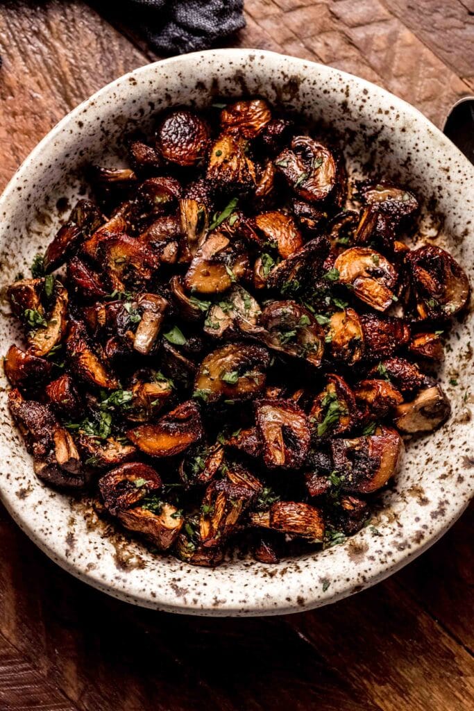 Air fryer mushrooms in bowl topped with minced parsley. 