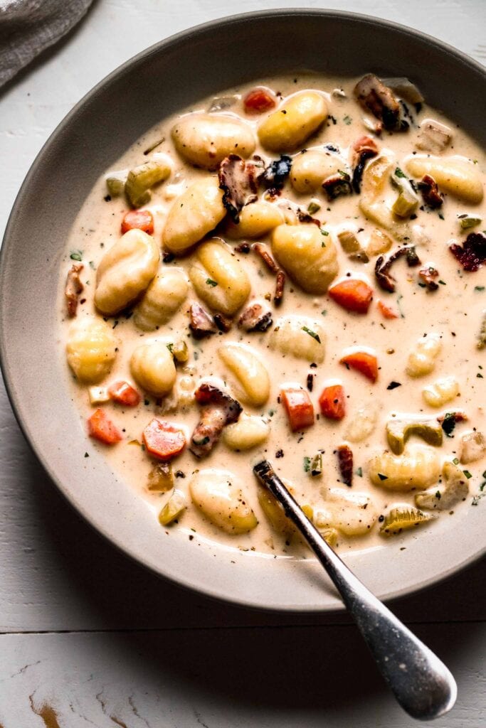 Bowl of creamy gnocchi soup with spoon.