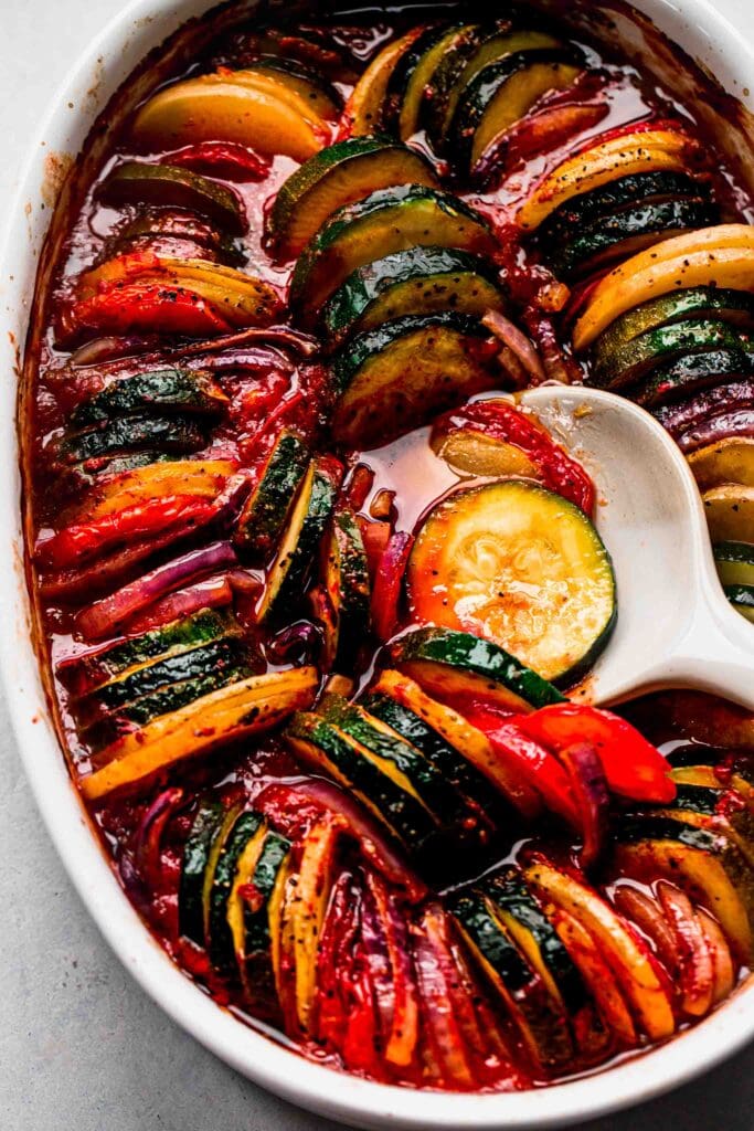 Briam roasted vegetables in baking dish with serving spoon.