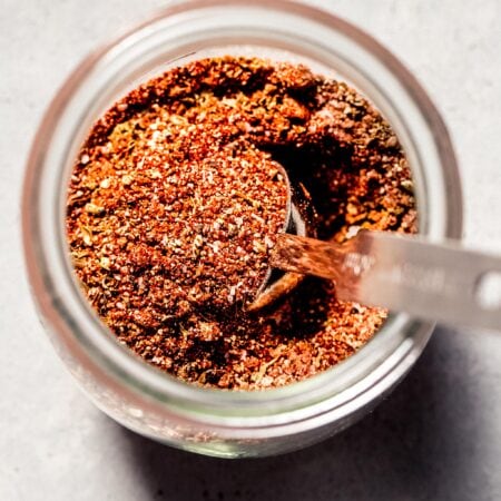 Chicken dry rub in glass jar with spoon.