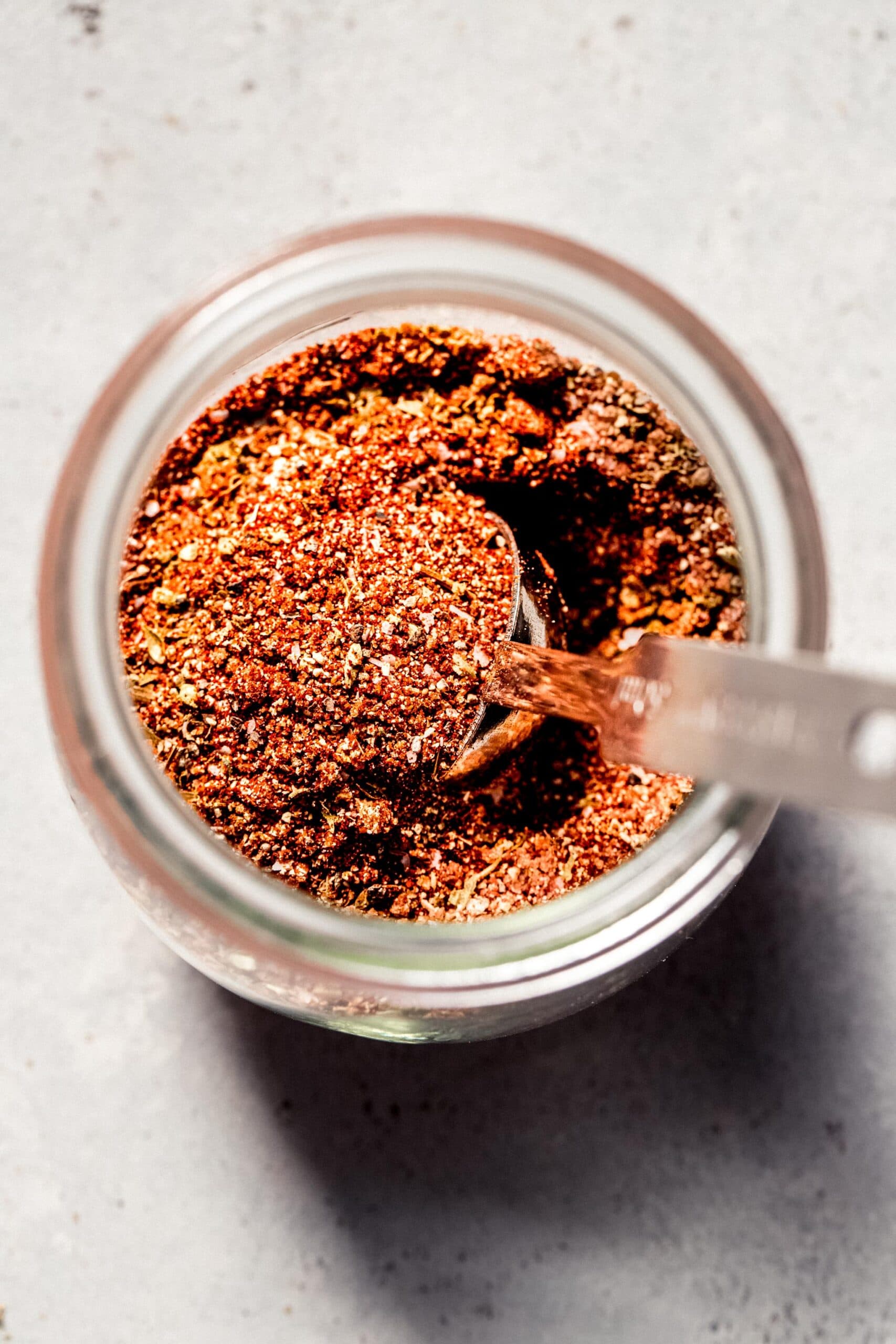 Chicken dry rub in glass jar with spoon.