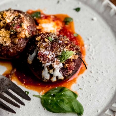Two stuffed mushrooms on plate with fork.