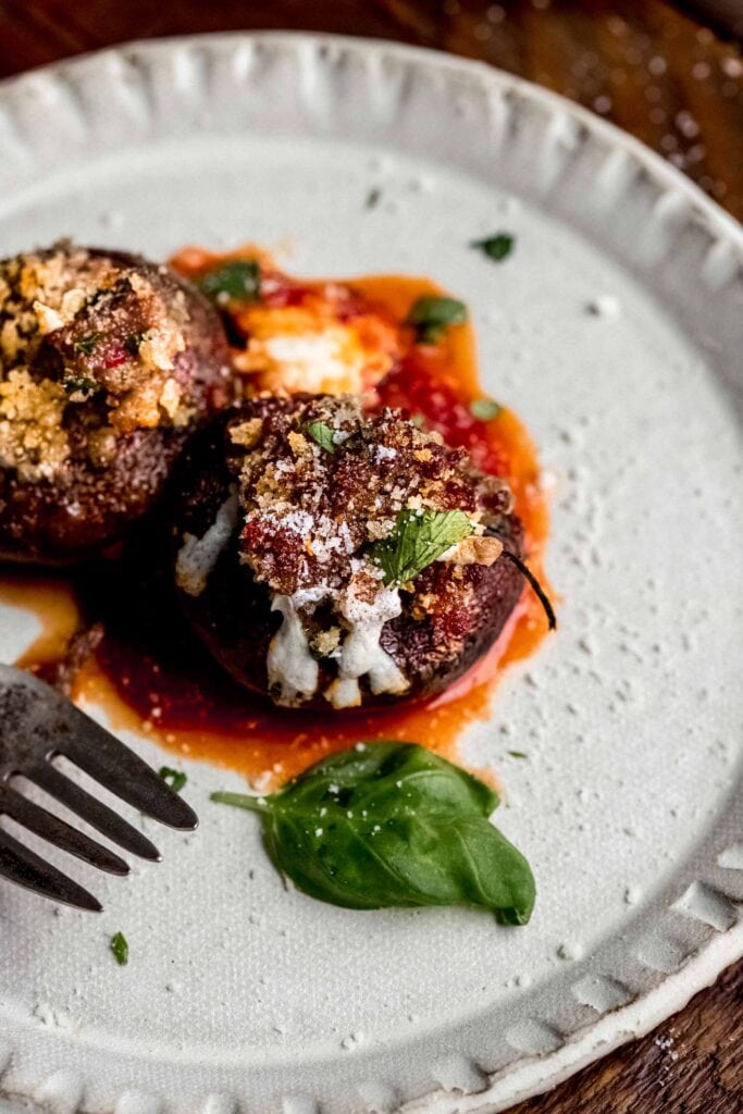 Two stuffed mushrooms on plate with fork.