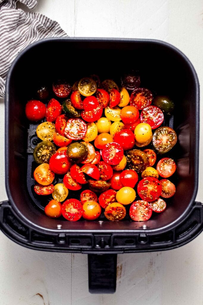 Tomato halves in air fryer basket before cooking.