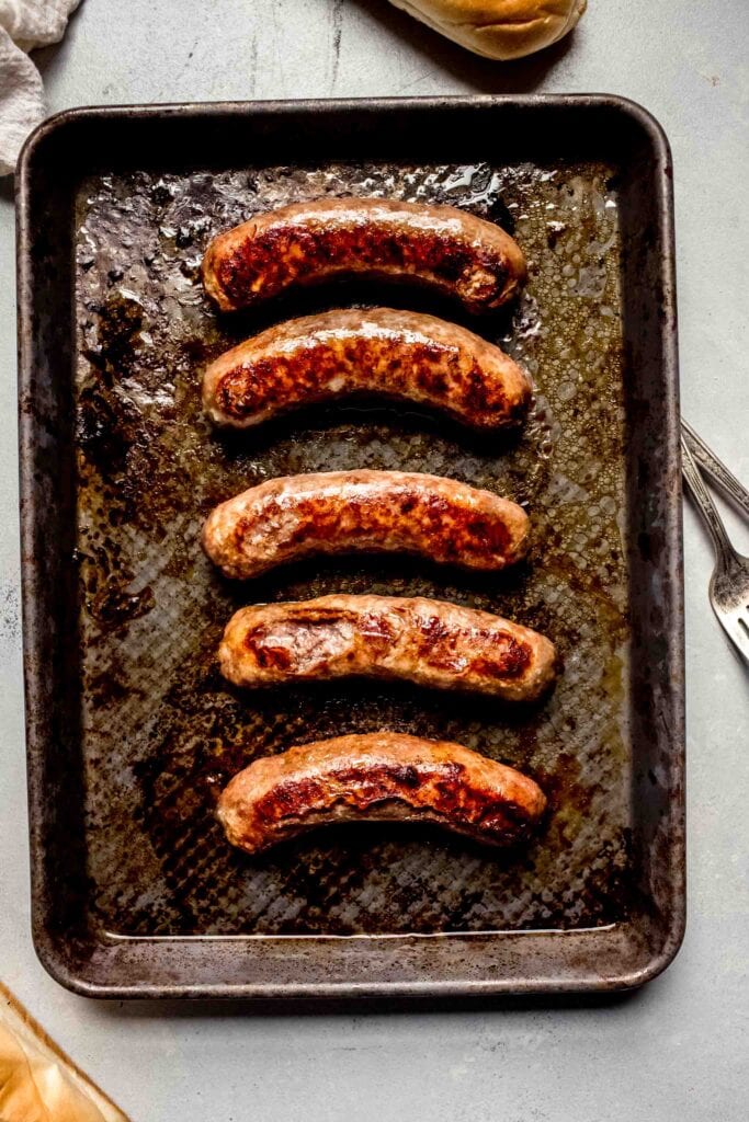 Cooked bratwurst on baking sheet.