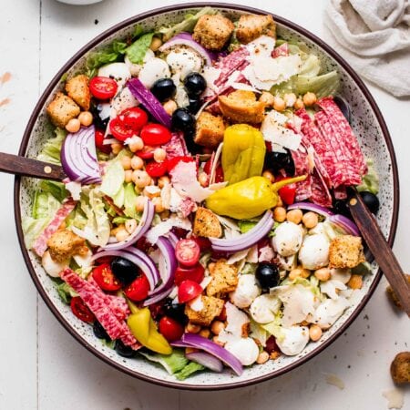 Italian chopped salad in large bowl on white table.