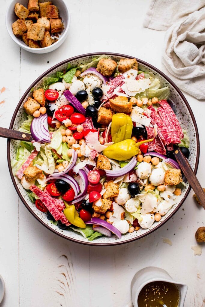 Italian chopped salad in large bowl on white table.