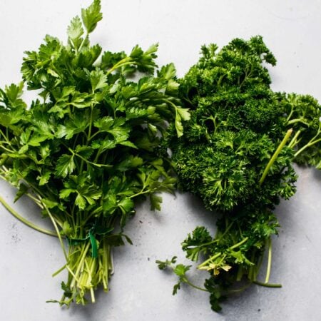 Two bundles of fresh parsley on counter.