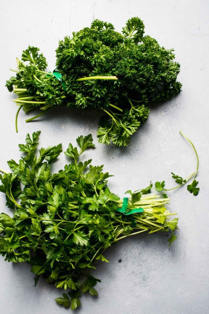 Bundle of flat leaf parsley and curly parsley on counter. 