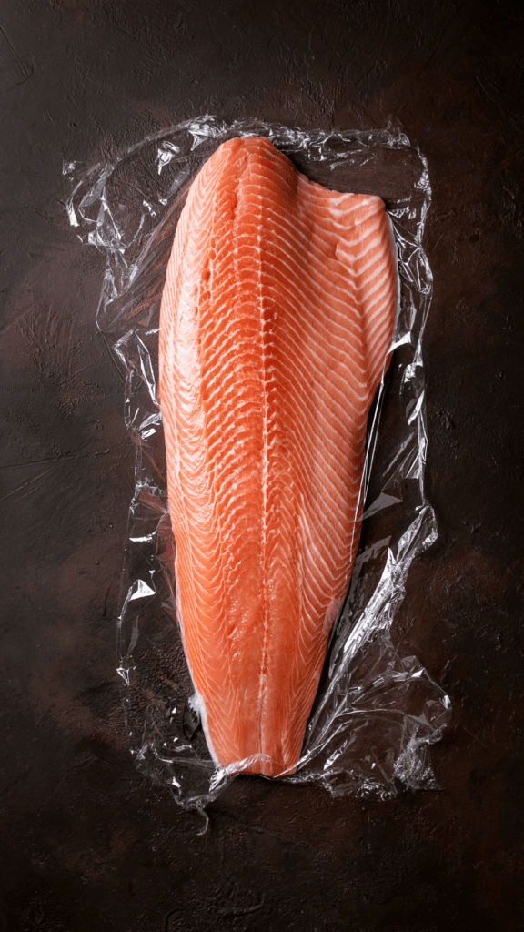 Salmon filet on saran wrap on counter.