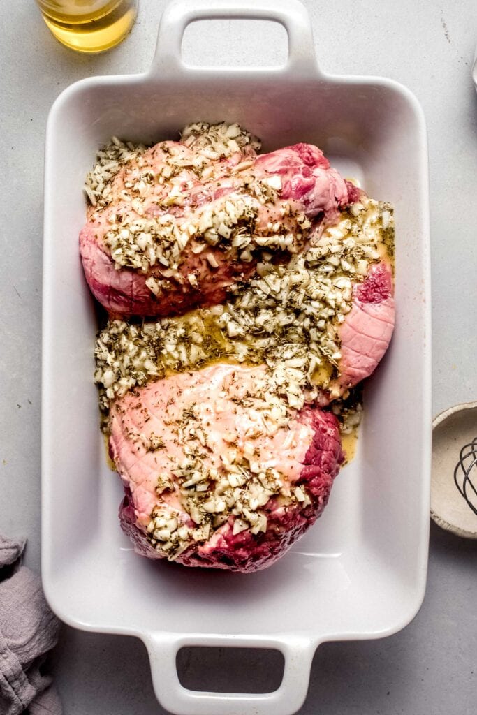 Butterfiled leg of lamb marinating in baking dish. 