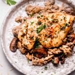 Chicken breast on top of creamy orzo on serving plate.