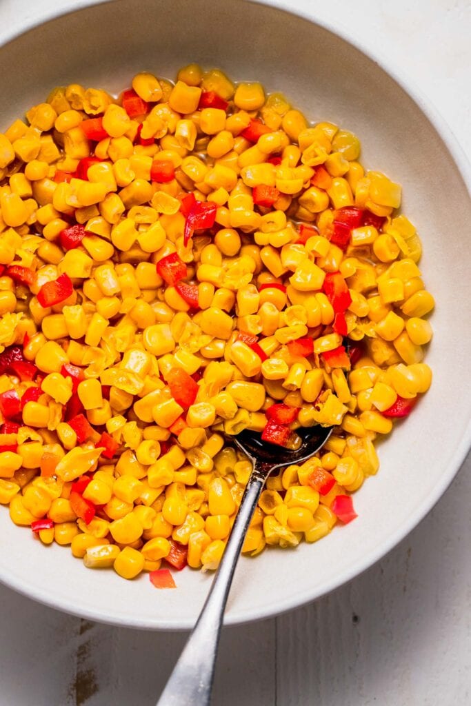 Cooked corn and red peppers in serving bowl. 