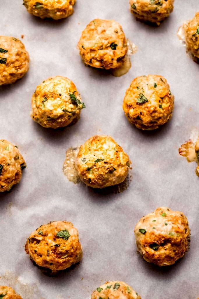 Close up of baked chicken meatballs on baking sheet.