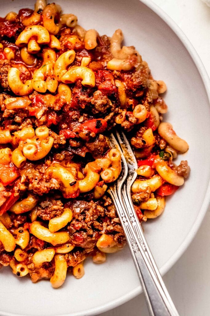 Close up of goulash served in white bowl with spoon.