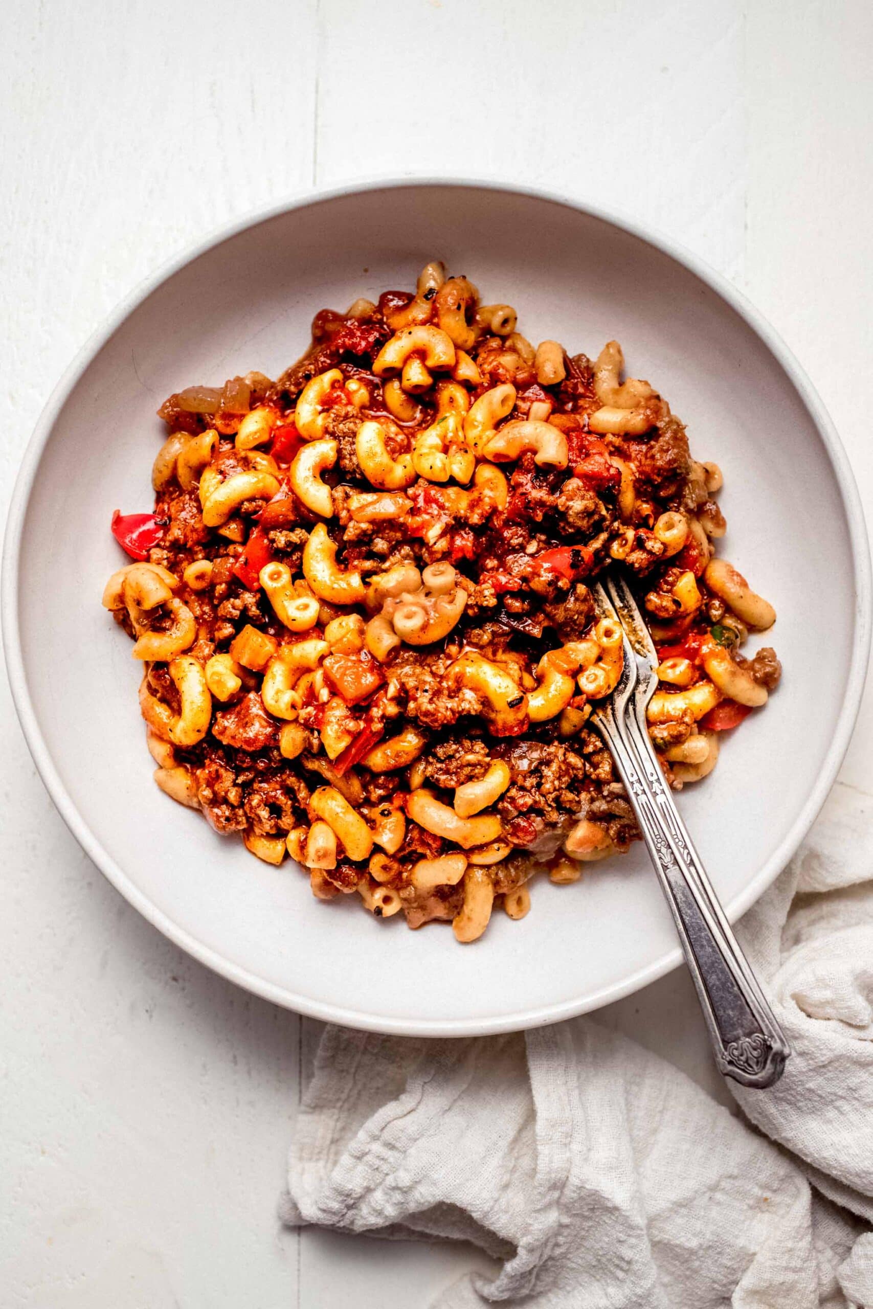 Overhead shot of goulash served in white bowl with spoon.