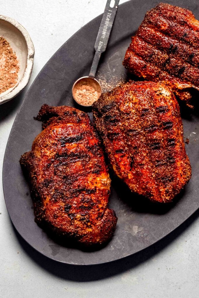 Traeger smoked pork chops on plate with spoonful of dry rub seasoning.