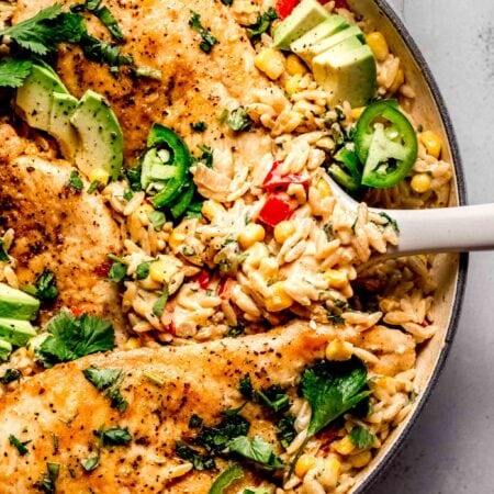 Cajun chicken orzo in skillet with serving spoon.