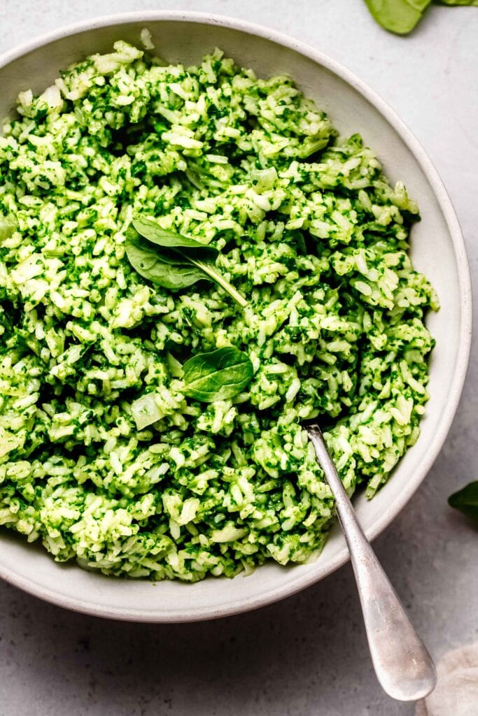 Spinach rice in white serving bowl with spoon.