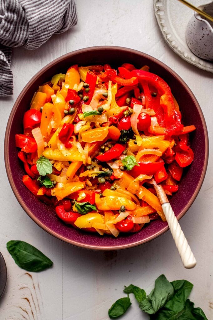 Pepperonata in large red bowl with spoon. 