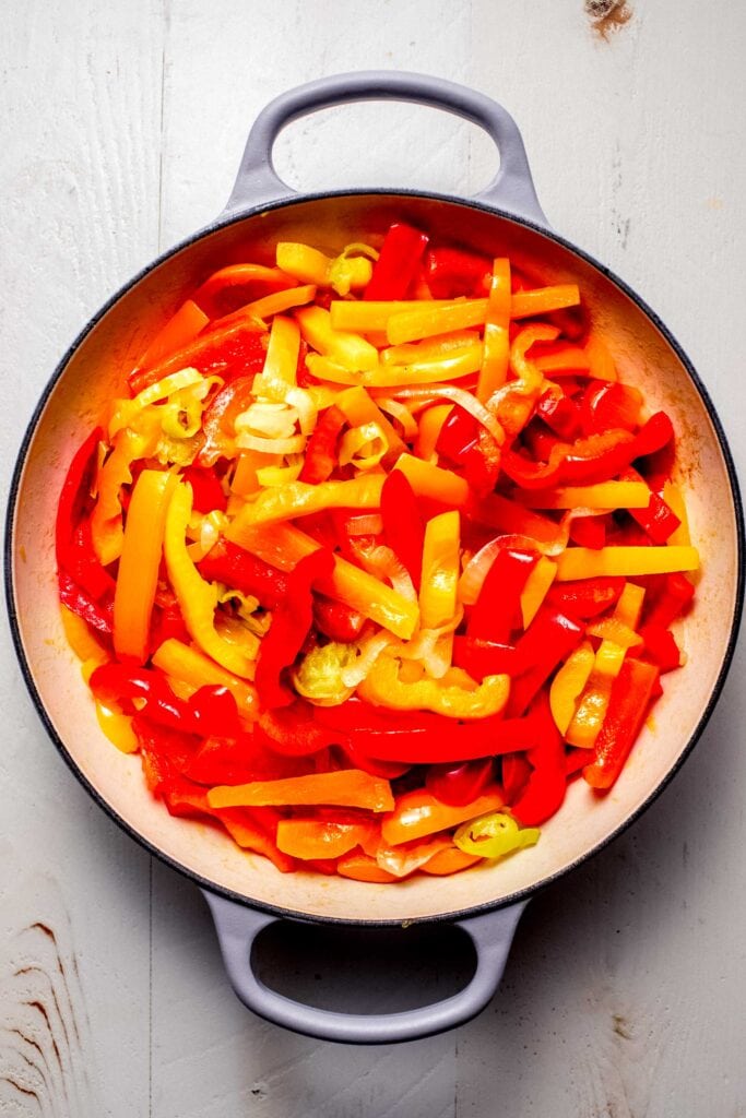 Sliced peppers added to skillet. 