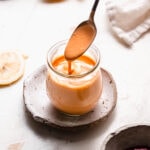 Spoon drizzling sriracha mayo into small glass jar.