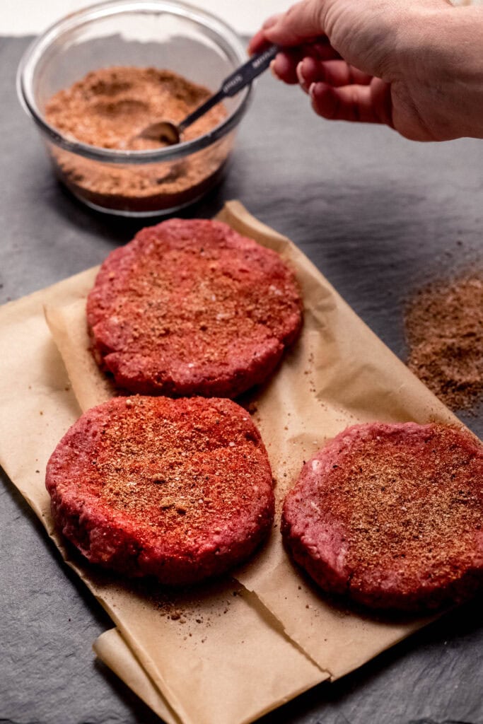 Hand dipping into bowl of burger seasoning.