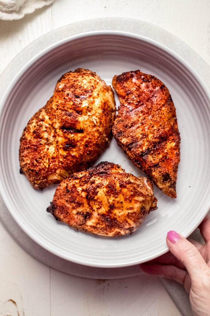 Cooked dry rubbed chicken breasts on serving plate.