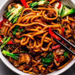 Overhead shot of bowl of yaki udon with black chopsticks.