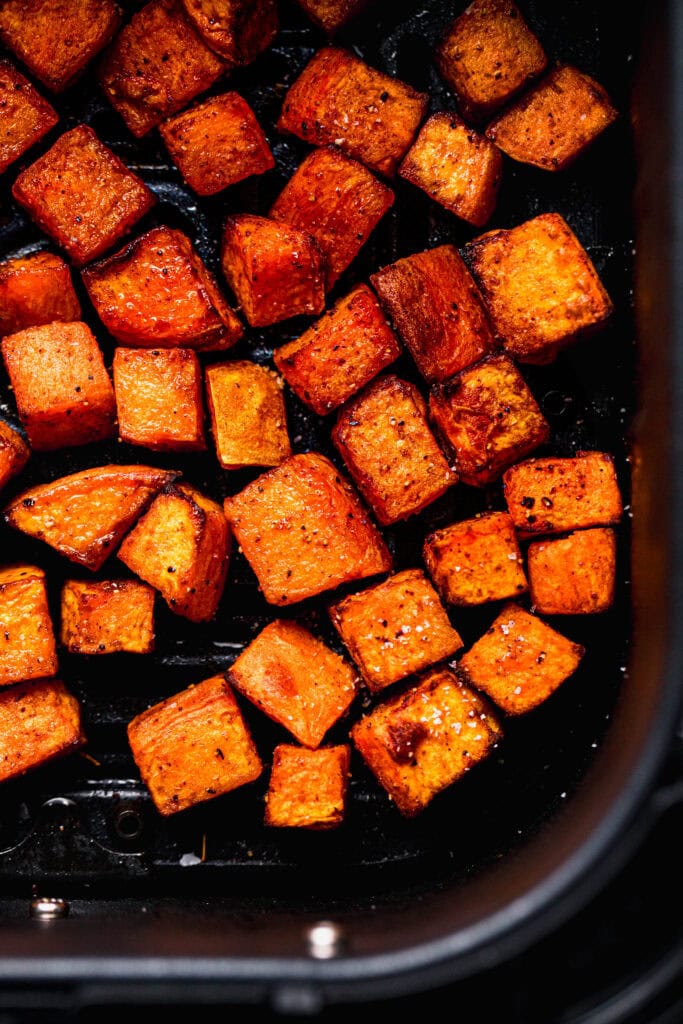 Golden sweet potatoes in air fryer basket.