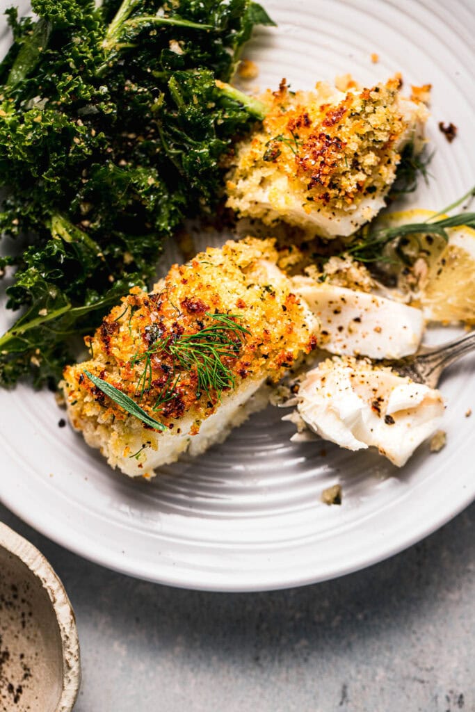 Overhead shot of crispy baked cod on plate next to vegetables. 