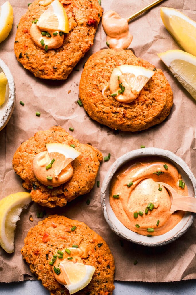 Lobster cakes on sheet of parchment paper dolloped with lobster cake sauce.