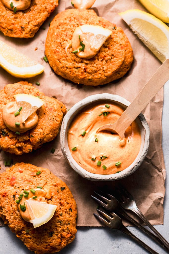 Lobster cake sauce in bowl next to prepared lobster cakes.