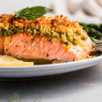Side view of pesto crusted salmon on serving plate.