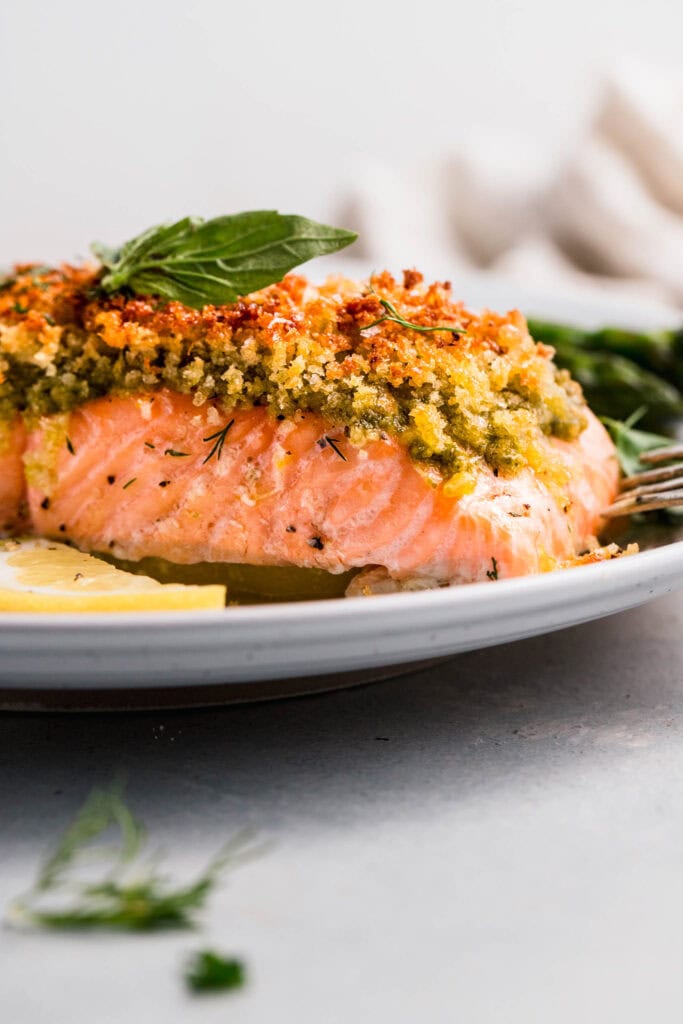 Side view of pesto crusted salmon on serving plate.