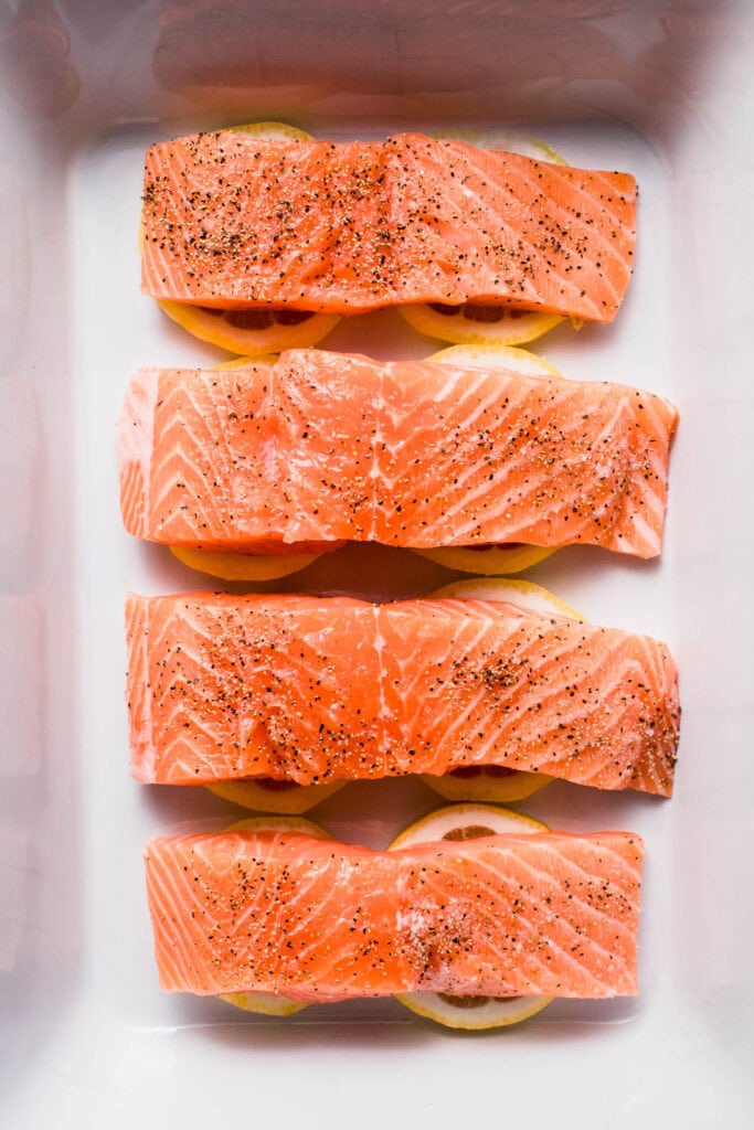 Salmon filets placed on top of lemons. 