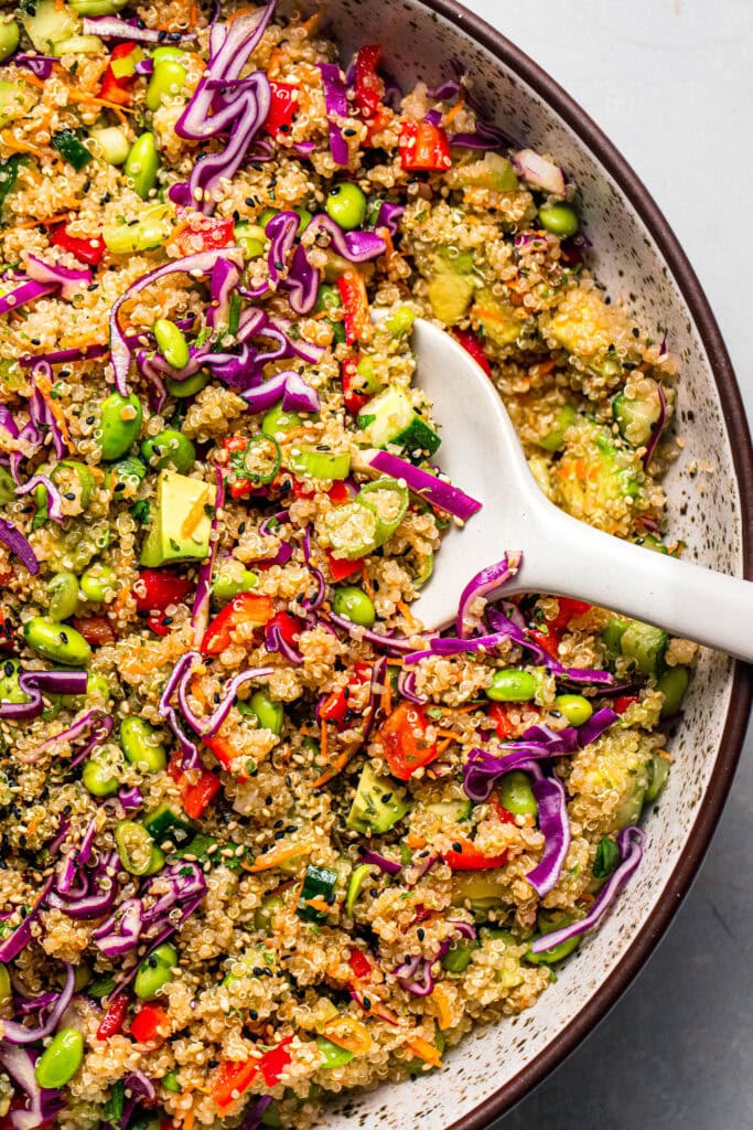 Overhead close up of edamame quinoa salad in bowl with serving spoon.