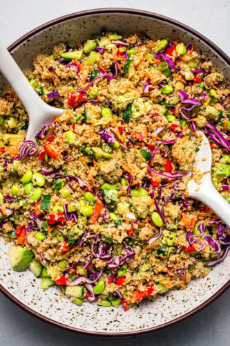 Overhead shot of Prepared asian quinoa salad in bowl with serving tongs.