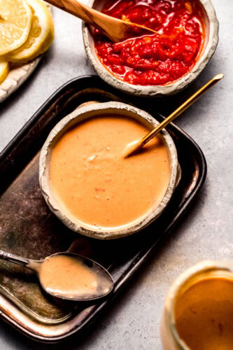 Creamy harissa sauce in small bowl next to spoon.