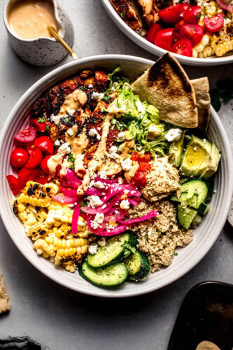 Overhead shot of assembled harissa chicken bowl with slices of pita.