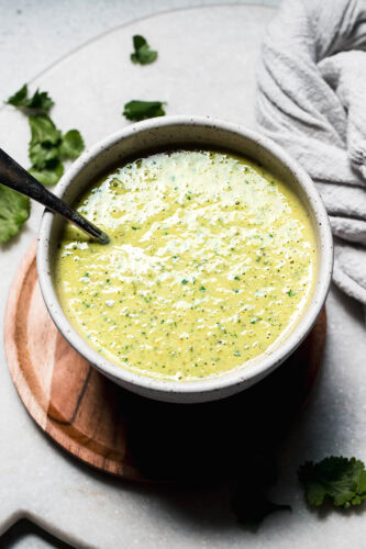 Poblano cream sauce in white bowl with serving spoon.