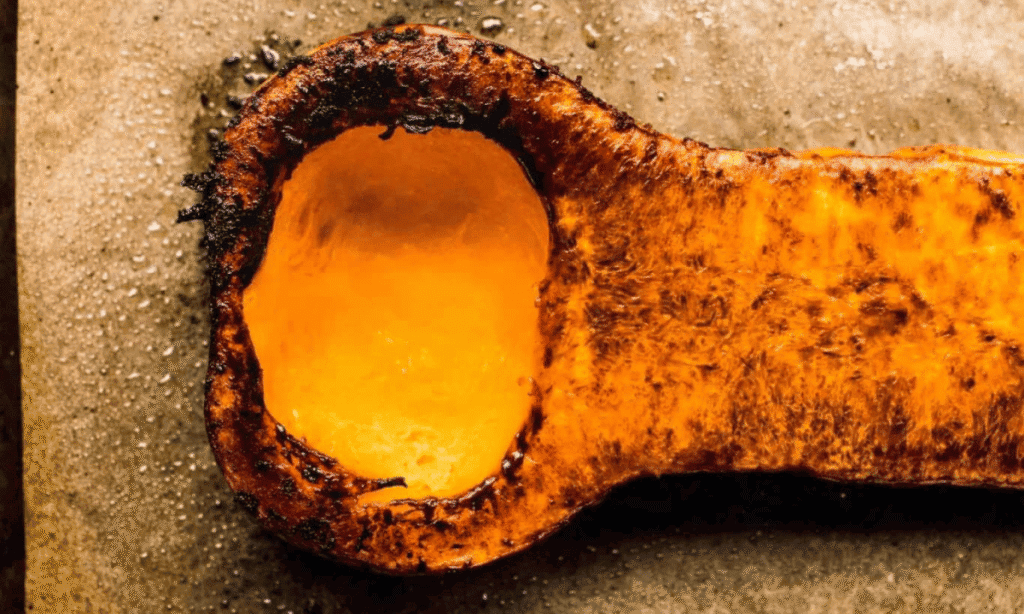 Halved butternut squash on baking sheet after roasting.