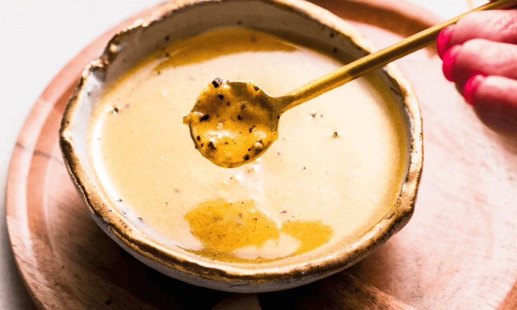 HAND HOLDING SPOONFUL OF LEMON PEPPER SAUCE.