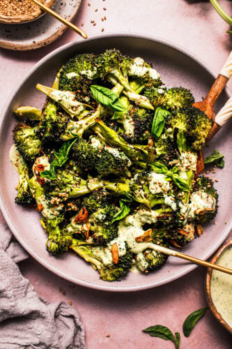 Overhead shot of bowl of broccoli drizzled with basil tahini dressing.