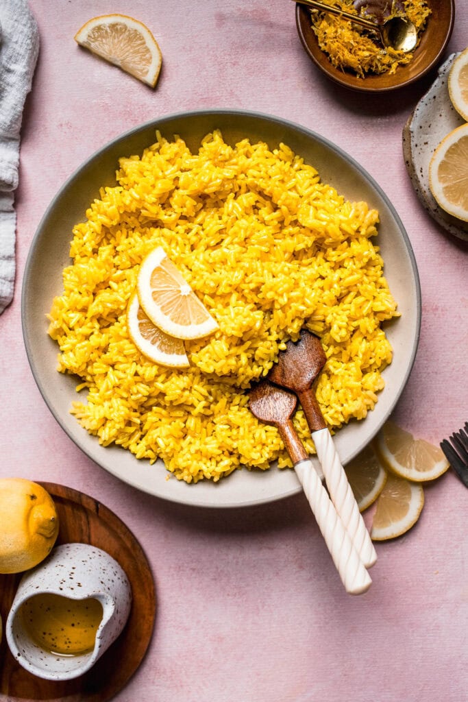 Overhead shot of greek lemon rice in serving bowl topped with lemon wedges.