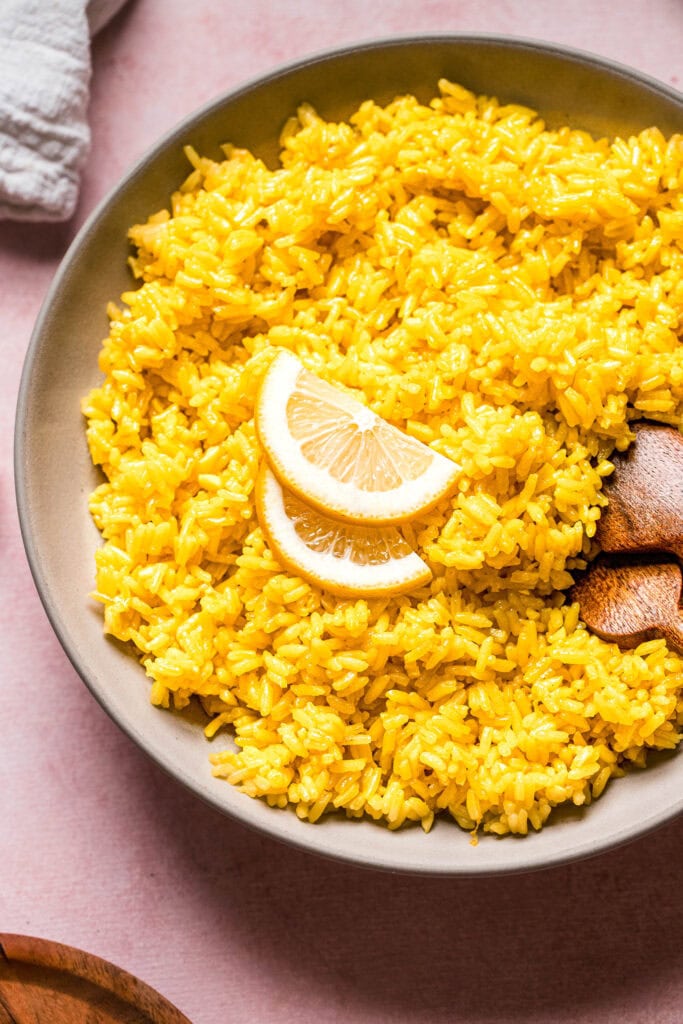 Overhead close up of greek lemon rice in bowl with serving spoons.