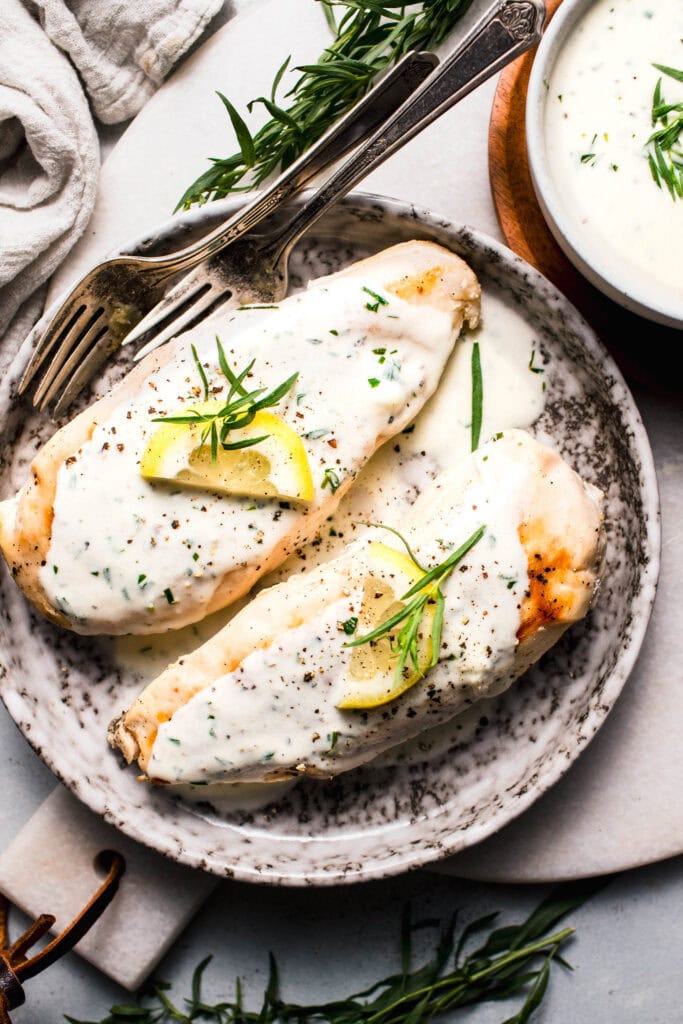 Two chicken breasts topped with creamy tarragon sauce.