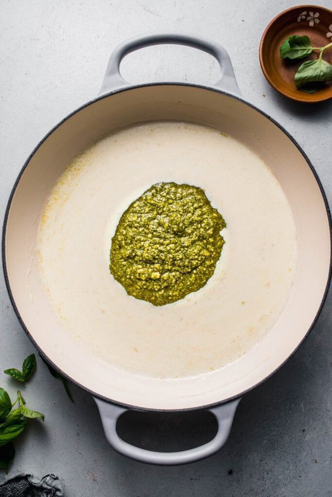 Skillet of cream sauce with dollop of pesto on top.