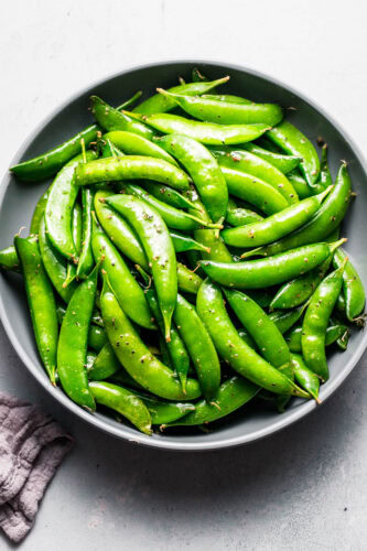 Overhead shot of bowl of sauteed snap peas in grey bowl.
