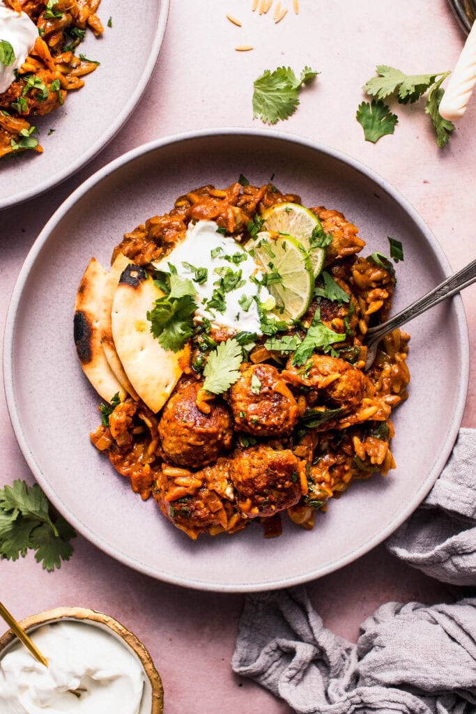 Overhead close up of butter chicken orzo in serving bowl with fork.